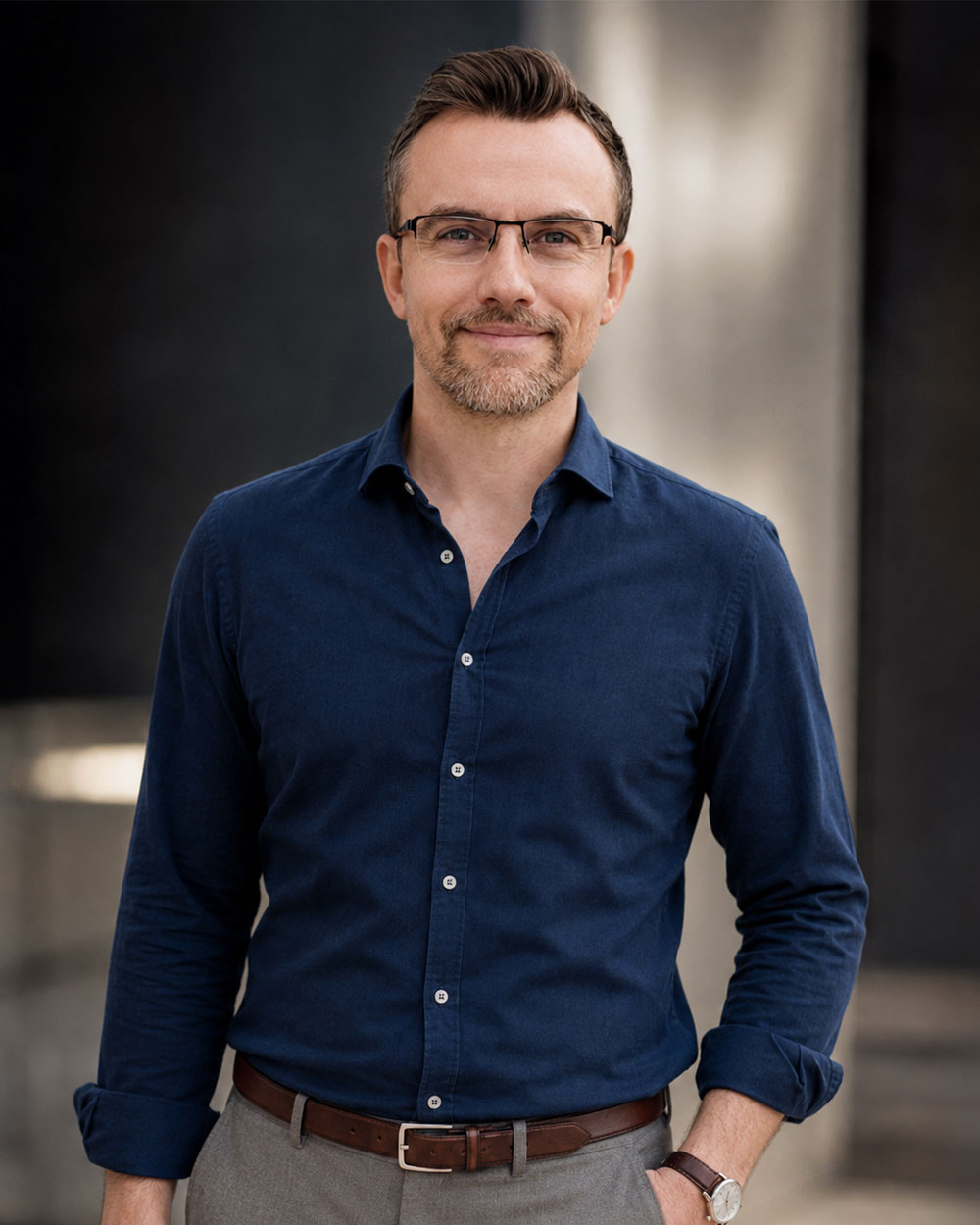 Michał Wcisło, właściciel Droppo / Kreacje Graficzne, w granatowej koszuli na tle betonowej elewacji